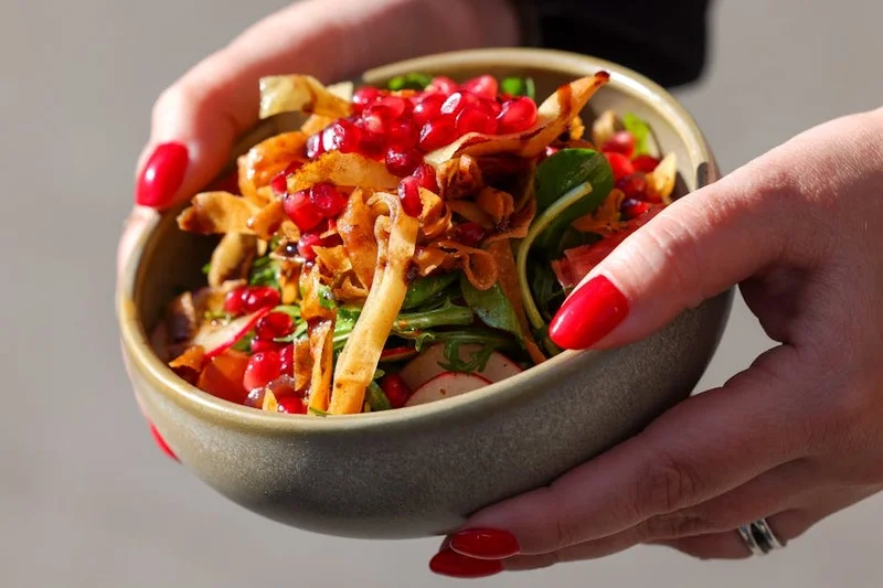 Izgara tavuk, avokado, nar ve karışık yeşilliklerle dolu canlı, sağlıklı bir salata kasesi