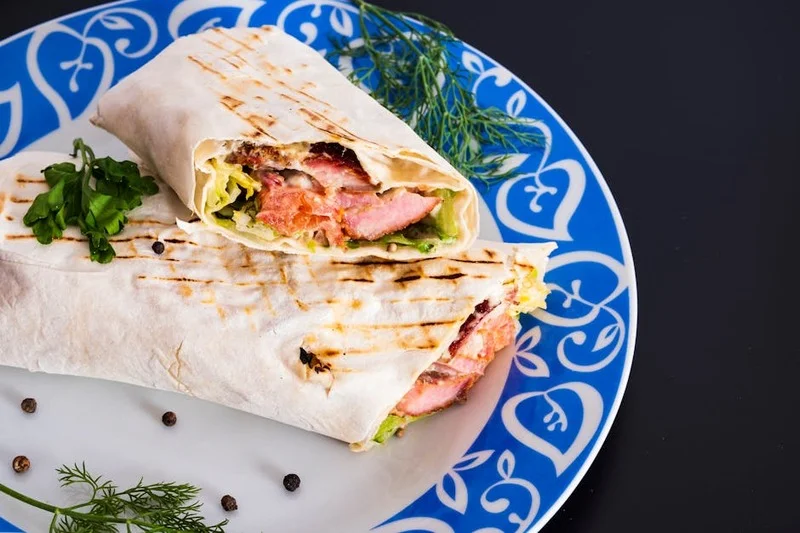 Izgara tavuk, taze sebzeler ve tam buğday tortillalı, mükemmel sarılmış sağlıklı bir protein dürüm