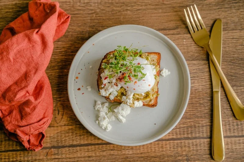 Avokado tost, poşe yumurta ve taze yeşilliklerle modern brunch tabağı